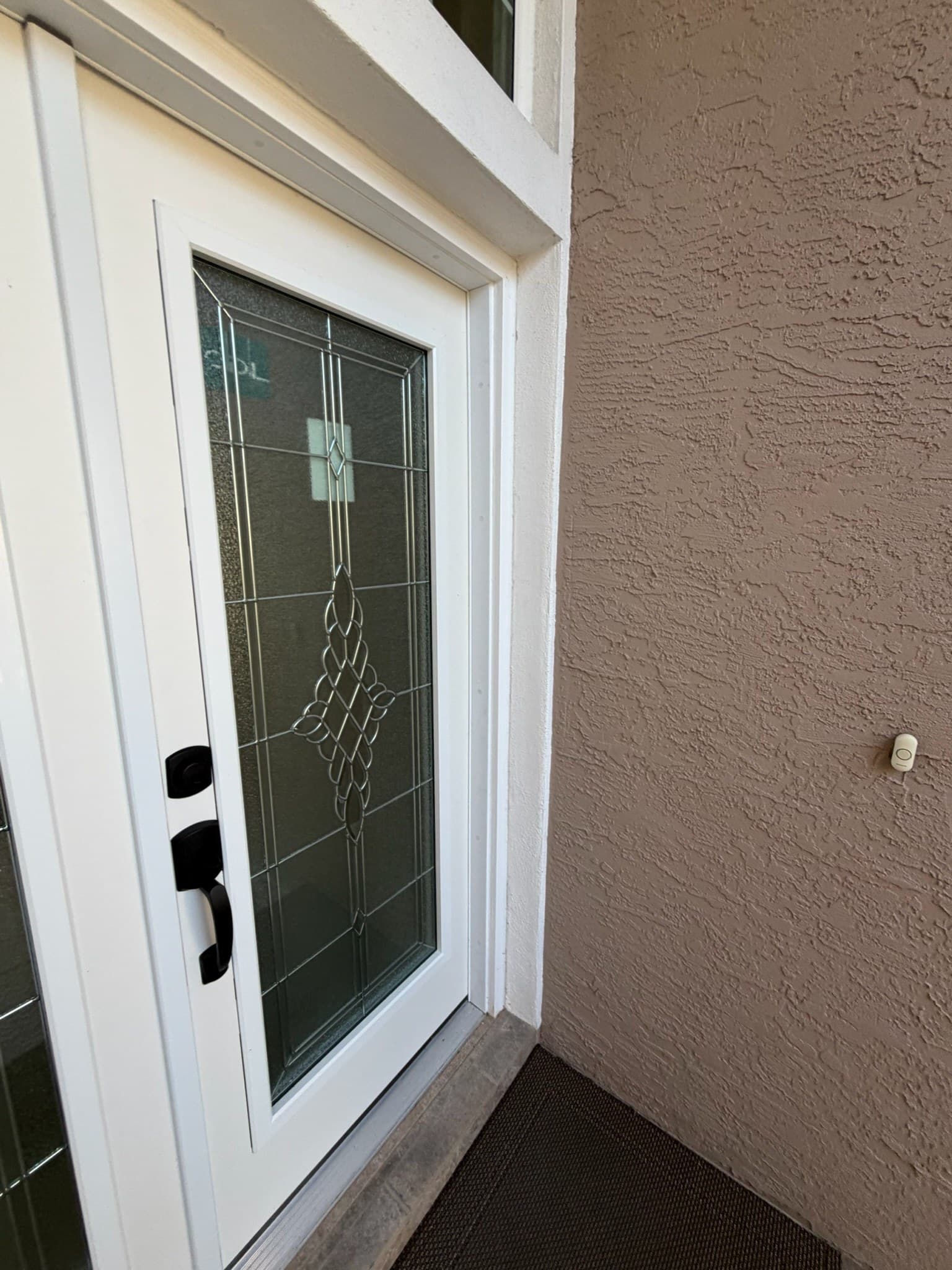 A white door with a decorative diamond-patterned glass insert and black hardware