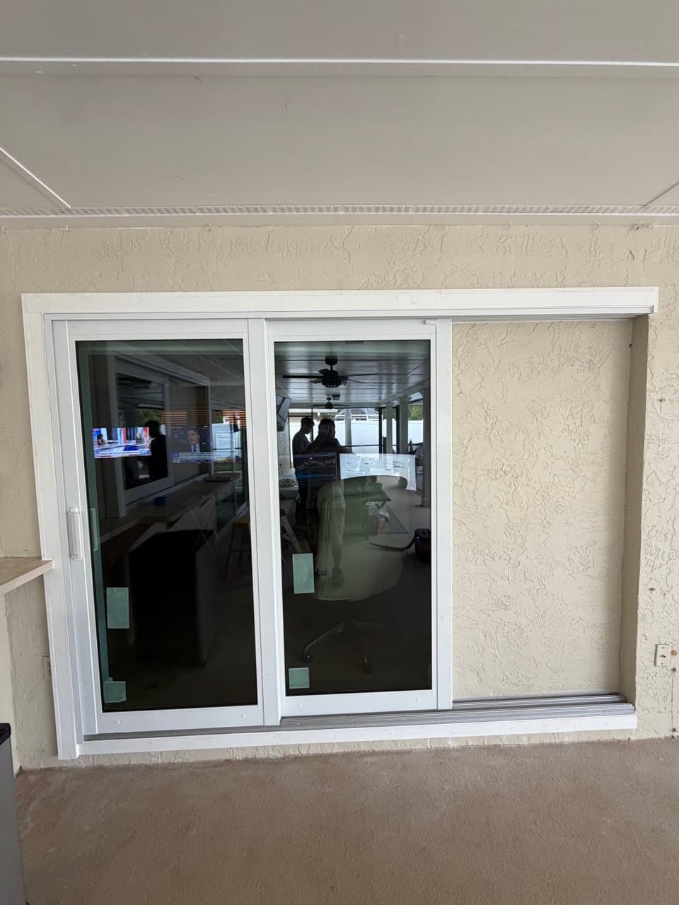 A three-panel white sliding patio door with the sill track and threshold exposed along the bottom