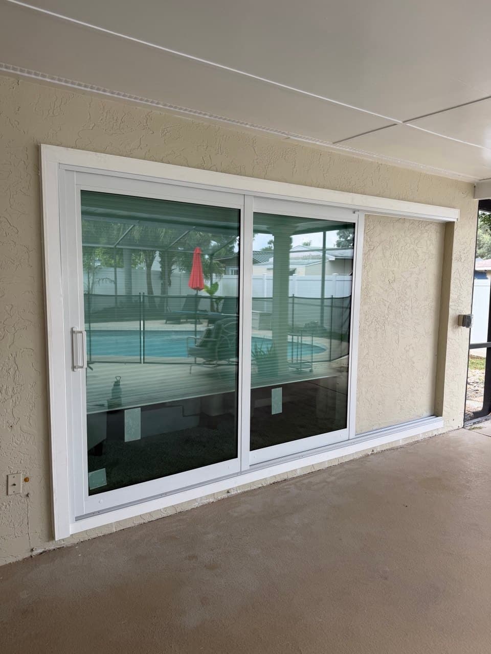 A three-panel white-framed sliding patio door newly fitted into a stucco wall