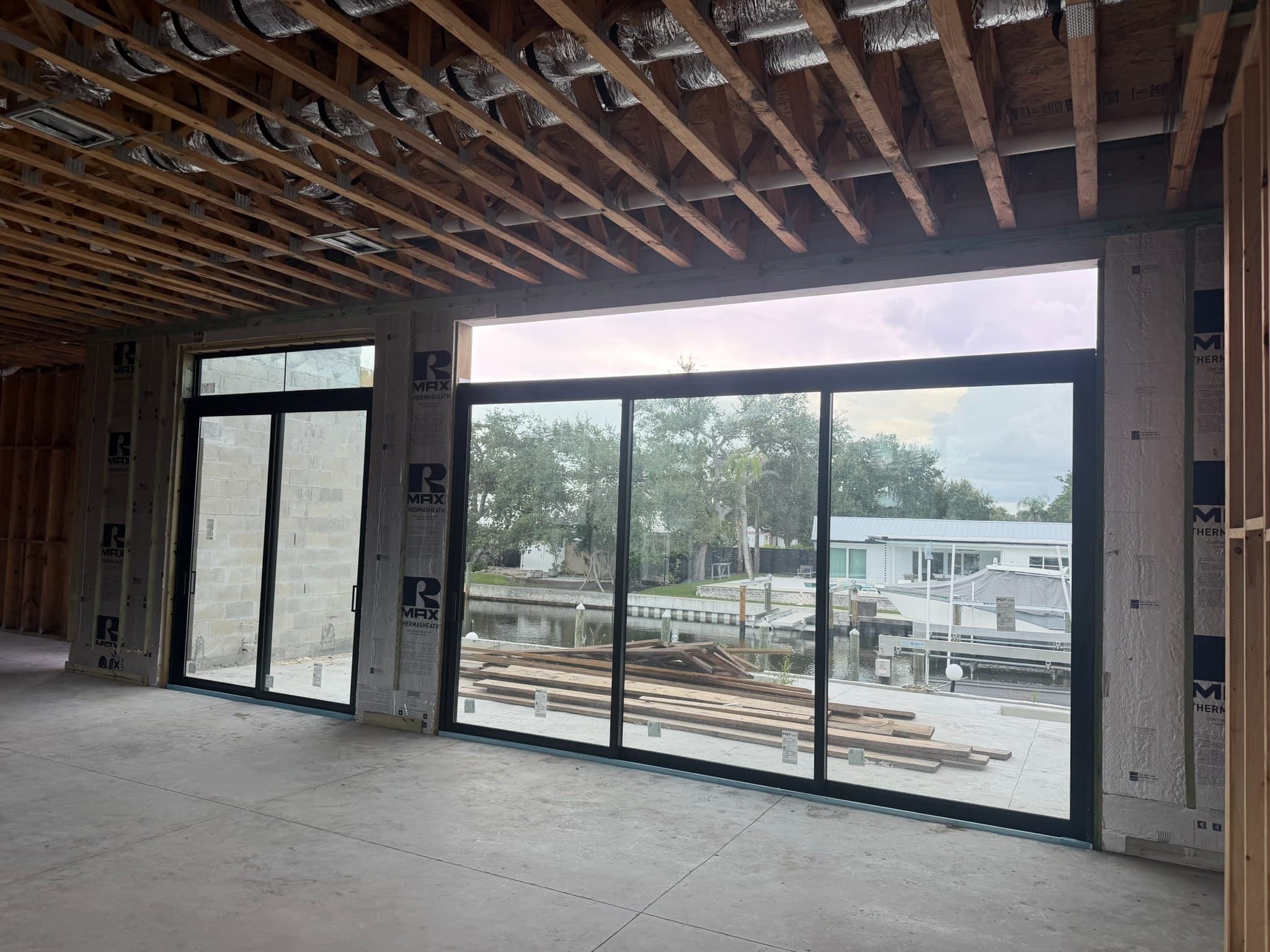 Large black-framed sliding glass doors set in a house under construction