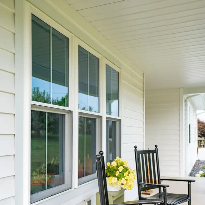 Double-hung windows along a covered porch with rocking chairs